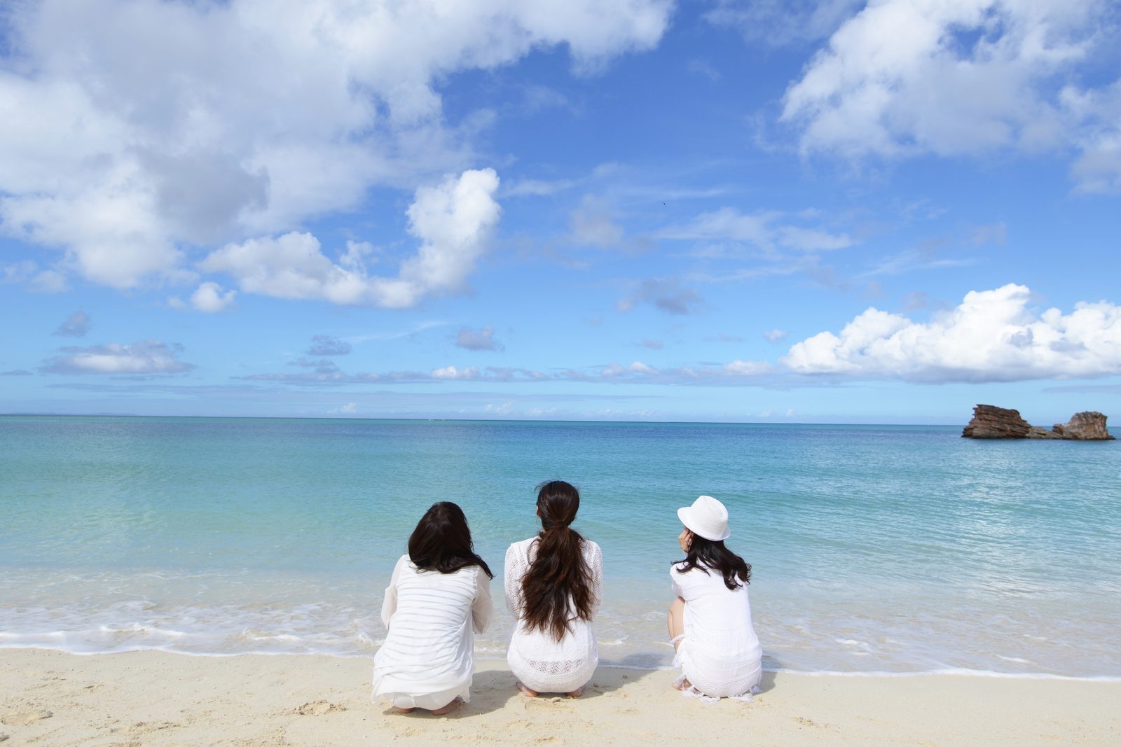 沖縄の浜辺で海の彼方を眺める人たち